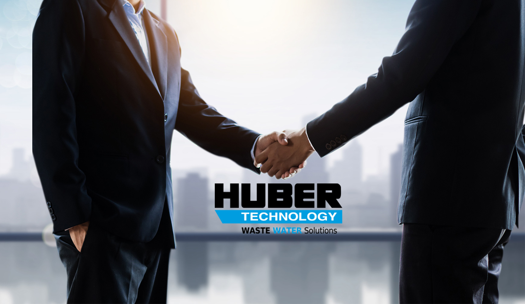 Two people in business suits shake hands in front of large windows, with the Huber Technology Waste Water Solutions logo displayed prominently in the center of the image.